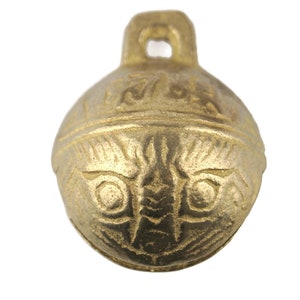 May include: A gold-colored metal bell with a decorative design. The bell has a loop at the top for hanging.