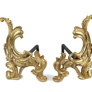 May include: A pair of ornate gold and black fireplace andirons with a scrolled design.