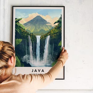 May include: A framed poster featuring a colourful illustration of a waterfall in a lush green jungle setting. The poster depicts a mountain in the background and the text "JAVA INDONESIA" at the bottom.