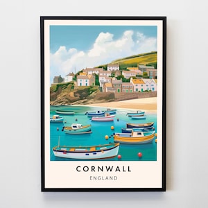 May include: A framed art print of Cornwall, England, featuring a coastal village scene. The artwork depicts colorful boats floating in turquoise water, with a hillside village in the background. The sky is blue with fluffy white clouds. The word "Cornwall" is printed at the bottom.