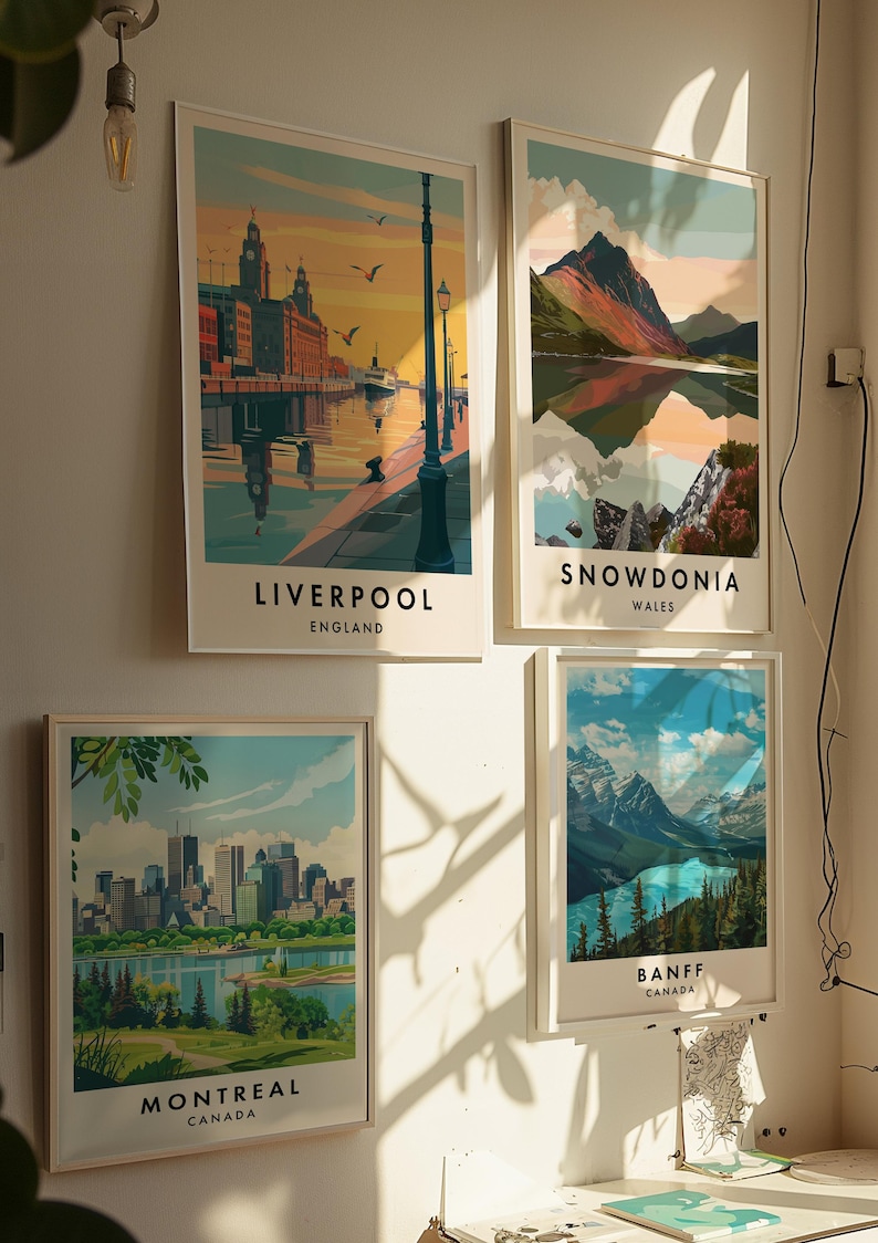 May include: Four framed travel posters with colorful illustrations of cityscapes and landscapes. The posters feature the cities of Liverpool, England, Snowdonia, Wales, Montreal, Canada, and Banff, Canada.