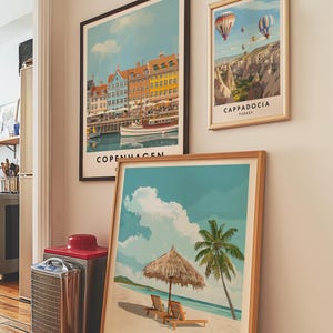 May include: Three framed travel posters on a white wall. The poster on the left shows a colorful cityscape with the text "Copenhagen" at the bottom. The poster in the middle shows a beach scene with a palm tree and a thatched umbrella. The text at the bottom reads "The Bahamas, Caribbean". The poster on the right shows a hot air balloon scene with the text "Cappadocia, Turkey".
