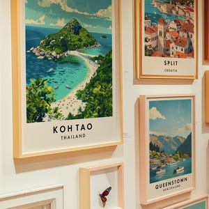 May include: A collection of framed travel posters featuring scenic destinations. The posters are in various colors and styles, with a butterfly specimen displayed in a smaller frame.