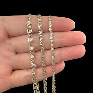May include: Three gold chains of different lengths and widths. The chains are made of a delicate, intricate design with a diamond-cut finish.