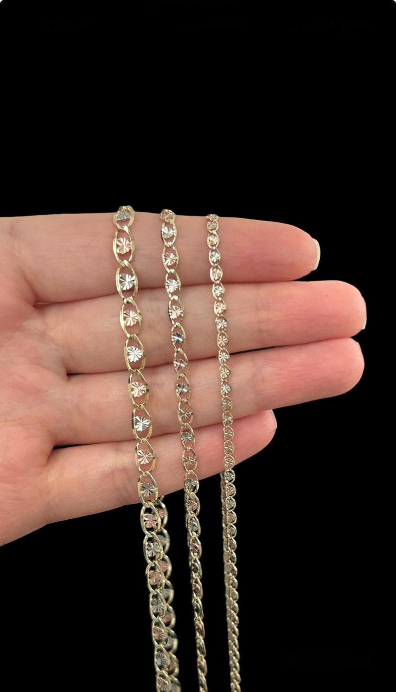 May include: Three gold chains of different lengths and widths. The chains are made of a delicate, intricate design with a diamond-cut finish.