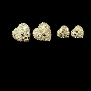 May include: A set of four gold heart-shaped earrings. The earrings are made of a textured metal that resembles a diamond pattern.