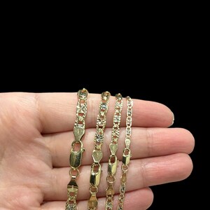 K&ouml;nnte beinhalten: Vier goldene Ketten in verschiedenen L&auml;ngen mit einem Diamant-Schliff-Design werden auf einer Hand gezeigt. Die Ketten sind aus 10 Karat Gold gefertigt und haben ein klassisches, elegantes Aussehen.