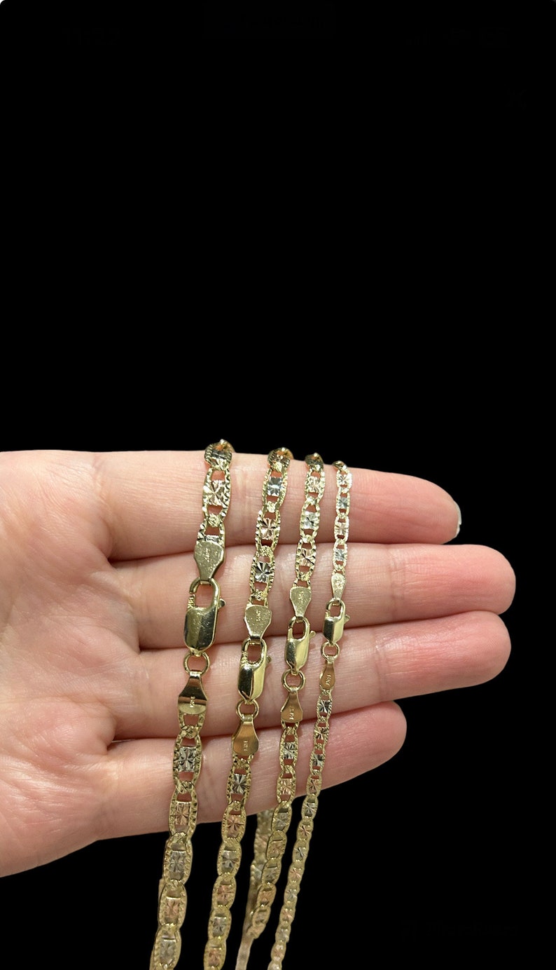 K&ouml;nnte beinhalten: Vier goldene Ketten in verschiedenen L&auml;ngen mit einem Diamant-Schliff-Design werden auf einer Hand gezeigt. Die Ketten sind aus 10 Karat Gold gefertigt und haben ein klassisches, elegantes Aussehen.