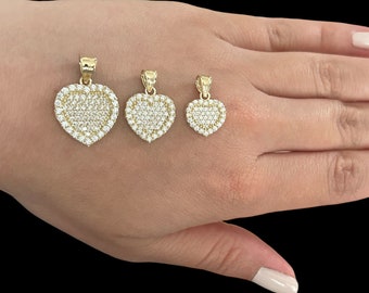 May include: Three gold heart-shaped pendants with clear cubic zirconia stones. The pendants are arranged in order of size, with the largest pendant on the left and the smallest pendant on the right.