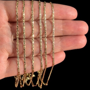 Pu&ograve; includere: Sei collane color oro con un delicato design a catena. Le collane sono tenute in una mano su uno sfondo nero. La parola "Wicked" &egrave; scritta in corsivo nella parte inferiore delle collane.