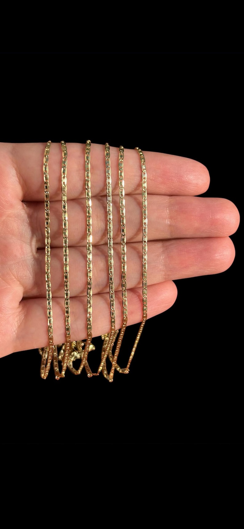 Pu&ograve; includere: Sei collane color oro con un delicato design a catena. Le collane sono tenute in una mano su uno sfondo nero. La parola "Wicked" &egrave; scritta in corsivo nella parte inferiore delle collane.