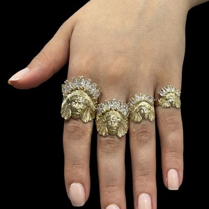 May include: Three gold rings featuring a Native American chief head design and clear cubic zirconia stones.