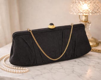 Bolso de mano vintage de satén negro con correa de cadena dorada y cierre de broche joya.