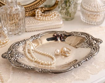 Bandeja ovalada vintage bañada en plata con intrincado diseño grabado y borde decorado con motivos florales.