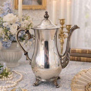 Vintage verzilverde theepot met sierlijk handvat en tuit op vier decoratieve poten