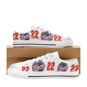 Op de afbeelding: Witte canvas lage sneakers met een rood en blauw patroon met de tekst "Indiana Fever" en het nummer "22".