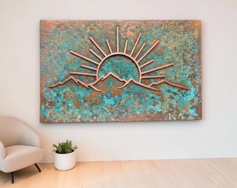 May include: A rectangular wall art piece featuring a copper-toned mountain range and a rising sun with radiating beams. The background has a textured, mottled finish with vibrant shades of turquoise, teal, and oxidized copper brown throughout.