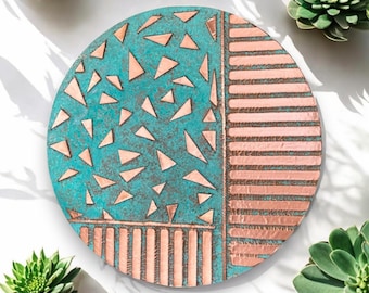 May include: A round copper tray with a geometric design. One half of the tray is turquoise blue with copper triangles, and the other half is copper with horizontal lines.