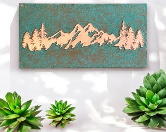 May include: A copper-colored metal wall art piece with a silhouette of mountains and trees against a teal green background.