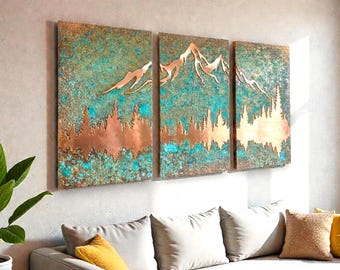 May include: A triptych of copper wall art depicting a mountain landscape. The artwork features a copper-colored mountain range and trees against a teal and brown background. The art is mounted on a wall above a sofa with pillows.