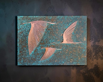 May include: A rectangular wall plaque featuring three metallic copper-toned birds in flight against a textured background with a mottled teal and bronze patina finish. The birds are depicted with detailed wing feathers and elongated necks.