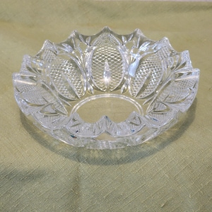 May include: A clear glass bowl with a decorative, cut-glass design. The bowl has a scalloped edge and a circular base.