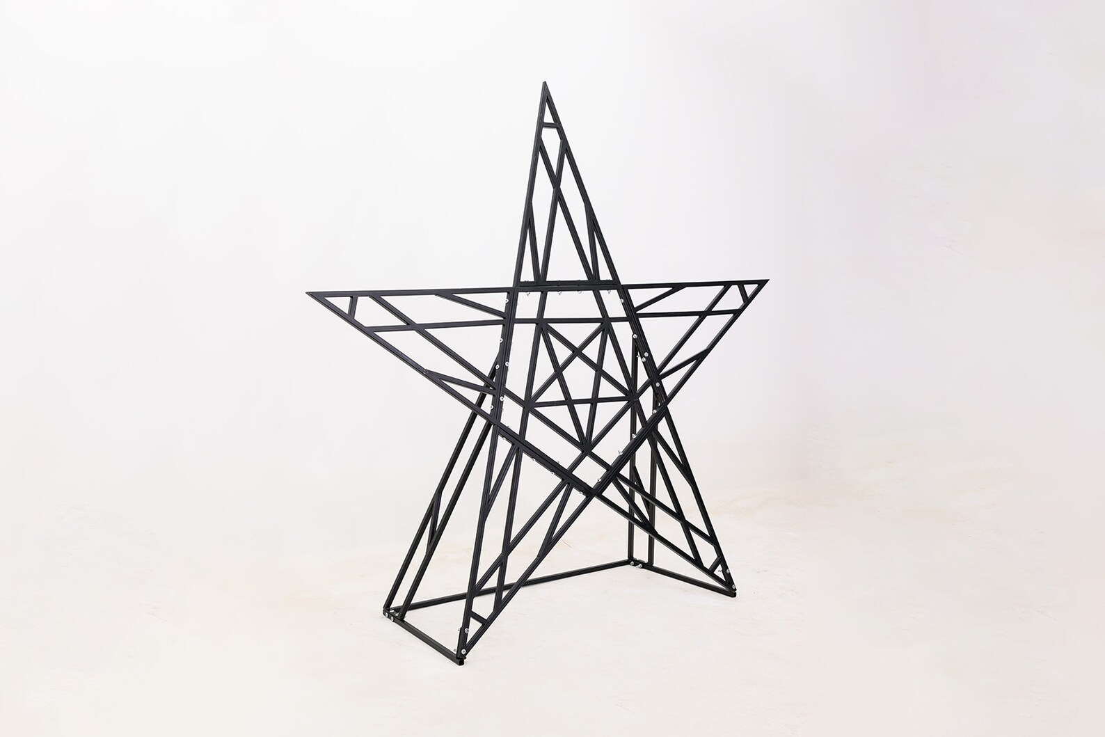 Freestanding metal bondage pentagram assembled upright, used for bdsm impact play and fetish restraint setups.