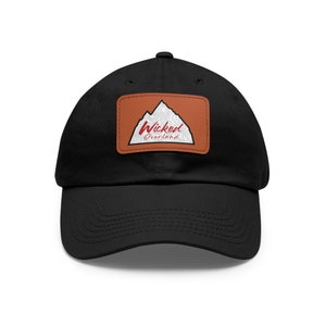 May include: Black baseball cap with a brown leather patch featuring a white mountain range and the text "Wicked Overland" in red.