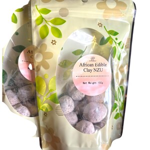 May include: A resealable bag with a clear window showing edible African clay Nzu. The bag is cream colored with a green floral pattern and the text "African Edible Clay Nzu" and "Net Weight 150g".