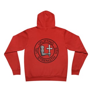 Puede incluir: Sudadera con capucha roja con un logotipo circular negro y gris en la espalda. El logotipo dice "Uplifting His Strength" con una imagen estilizada de una persona levantando una cruz.