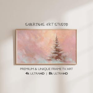Può includere: Dipinto di paesaggio incorniciato con una morbida tavolozza di colori pastello. L'opera presenta un albero sempreverde centrale in un ambiente innevato, con un cielo caldo e luminoso. Il testo "SABRINAS ART STUDIO" è in alto e "PREMIUM & UNIQUE FRAME TV ART" in basso.