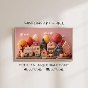 Könnte beinhalten: Ein gerahmtes Kunstwerk mit einer skurrilen Dorfszene mit Filzhäusern, Bäumen und Kürbissen. Das Kunstwerk ist vor einem rosa Hintergrund platziert, mit dem Text "SABRINAS ART STUDIO" oben und "PREMIUM & UNIQUE FRAME TV ART" und "4K ULTRAHD | 8K ULTRAHD" unten.