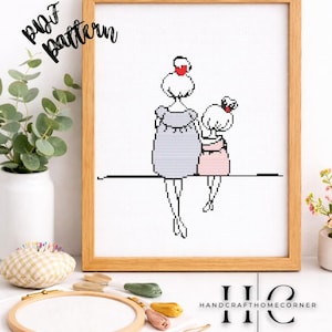 May include: Cross-stitch pattern framed in a light wood. The artwork depicts two figures, one larger and one smaller, seated side-by-side. The larger figure wears a gray dress, and the smaller figure wears a pink dress. The words "PDF pattern" are in the upper left corner.