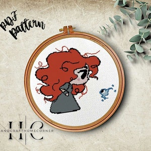 以下が含まれることがあります： 赤い髪の漫画の女の子と青い鳥のクロスステッチパターン。パターンは木製の刺繍枠に入っています。画像の上部に黒い文字で「DIY pattern」と書いてあります。