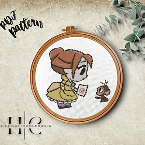 May include: Cross stitch pattern featuring a cartoon illustration of a girl with brown hair wearing a yellow dress and a monkey holding a piece of paper. The pattern is in a wooden embroidery hoop.