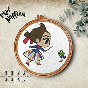 May include: A cross-stitch pattern featuring a cartoon girl in a blue and yellow dress holding a stick, and a green frog with a white hat. The pattern is framed in a wooden hoop.