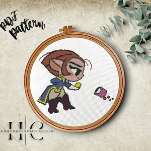 May include: Cross stitch pattern of a cartoon character with brown hair and a blue and gold jacket holding a yellow object. The character is looking at a pink object on the ground. The pattern is in a wooden embroidery hoop.