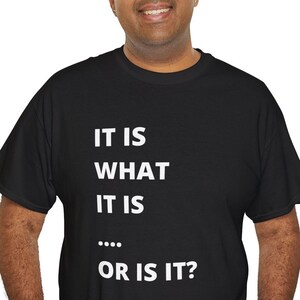 Puede incluir: Camiseta negra con texto blanco que dice "IT IS WHAT IT IS..... OR IS IT?"