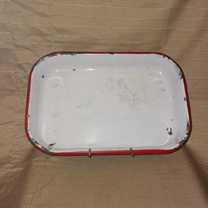 Molde rectangular de esmalte blanco para hornear con borde rojo.