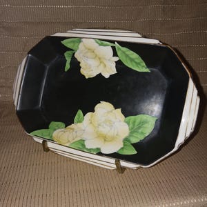May include: Black and white rectangular serving tray with a floral design. The tray features a black interior with yellow roses and green leaves. The edges are white with gold stripes.