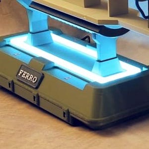May include: A futuristic-looking base with a rectangular shape, olive green exterior, and a glowing blue light. The base has the word "FERRO" on a small, rectangular plate. The design includes support structures and a light-emitting panel.