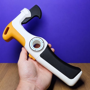 Puede incluir: Una herramienta manual con cuerpo blanco y negro y un acento amarillo en la parte superior. Incluye una hoja negra curva en la cabeza, un dial central circular con detalles en azul y un mecanismo de gatillo amarillo en el lateral del mango.