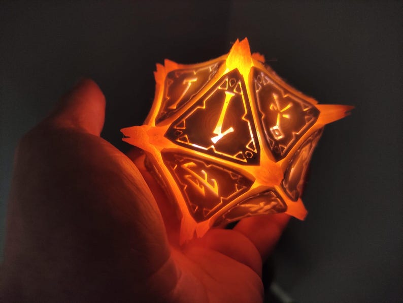 May include: A glowing orange and black 20-sided die with numbers and symbols on each face. The die is lit from within, casting a warm orange glow.