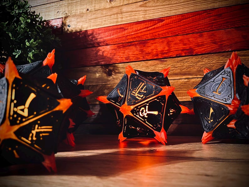 May include: Four black and orange dice with glowing yellow numbers. The dice are illuminated from within and are sitting on a wooden surface.