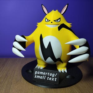May include: A yellow creature figurine with pointed ears, a wide grin, and large white claws on each hand. The figure features a black lightning bolt pattern on its chest and stands on a black circular base with a sign reading gamertag/small text.