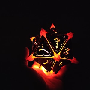 May include: A glowing, multi-sided, black metal dice with orange light shining through the cut-out designs.