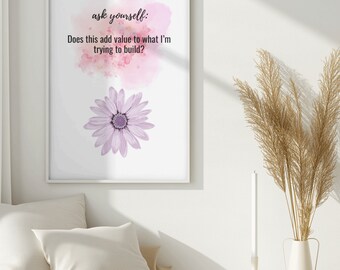 May include: A white framed print with a pink watercolor background and a purple flower. The text on the print reads "ask yourself: Does this add value to what I'm trying to build?"