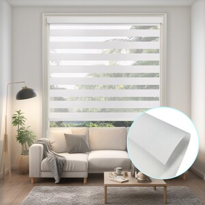 K&ouml;nnte beinhalten: Wei&szlig;e Zebra-Rollos mit einem strukturierten Stoff. Die Rollos sind in einem Wohnzimmer mit einem wei&szlig;en Sofa und einem Couchtisch installiert.