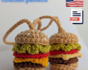 May include: Two crocheted hamburger ornaments with tan buns, green lettuce, red tomato, yellow cheese, and a brown patty. The text "Crochet pattern" is above the burgers. An American flag and a PDF icon are also present.