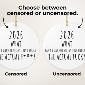 May include: Two white ceramic ornaments with gold string for hanging. Each ornament has the text "2026 WHAT (AND I CANNOT STRESS THIS ENOUGH) THE ACTUAL F***?" and "2026 WHAT (AND I CANNOT STRESS THIS ENOUGH) THE ACTUAL FUCK?" with the words "Censored" and "Uncensored" below.